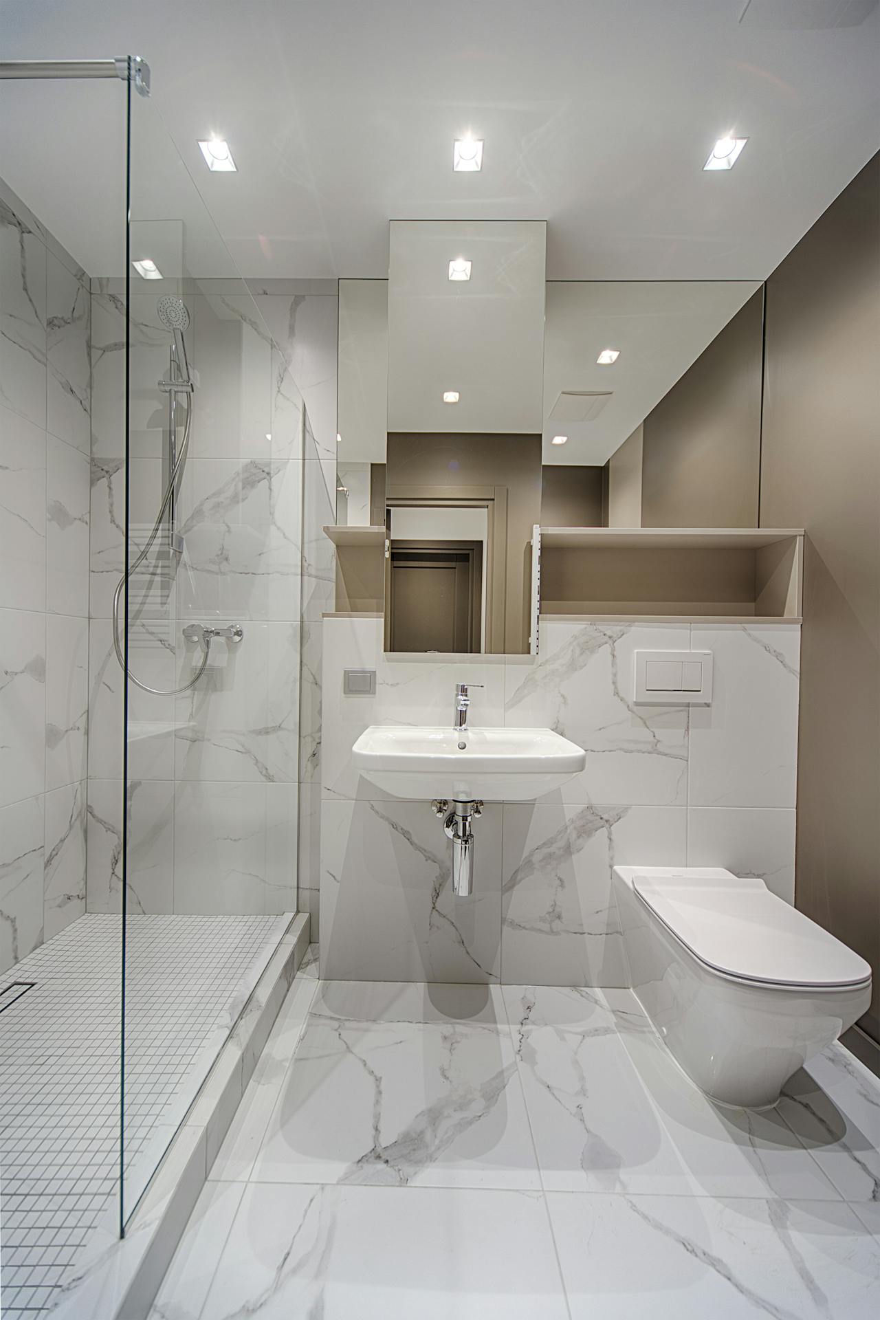 Modernes Badezimmer mit Glas-Duschabtrennung, Marmorfiesen, Wand-WC und elegantem Waschbecken-Design