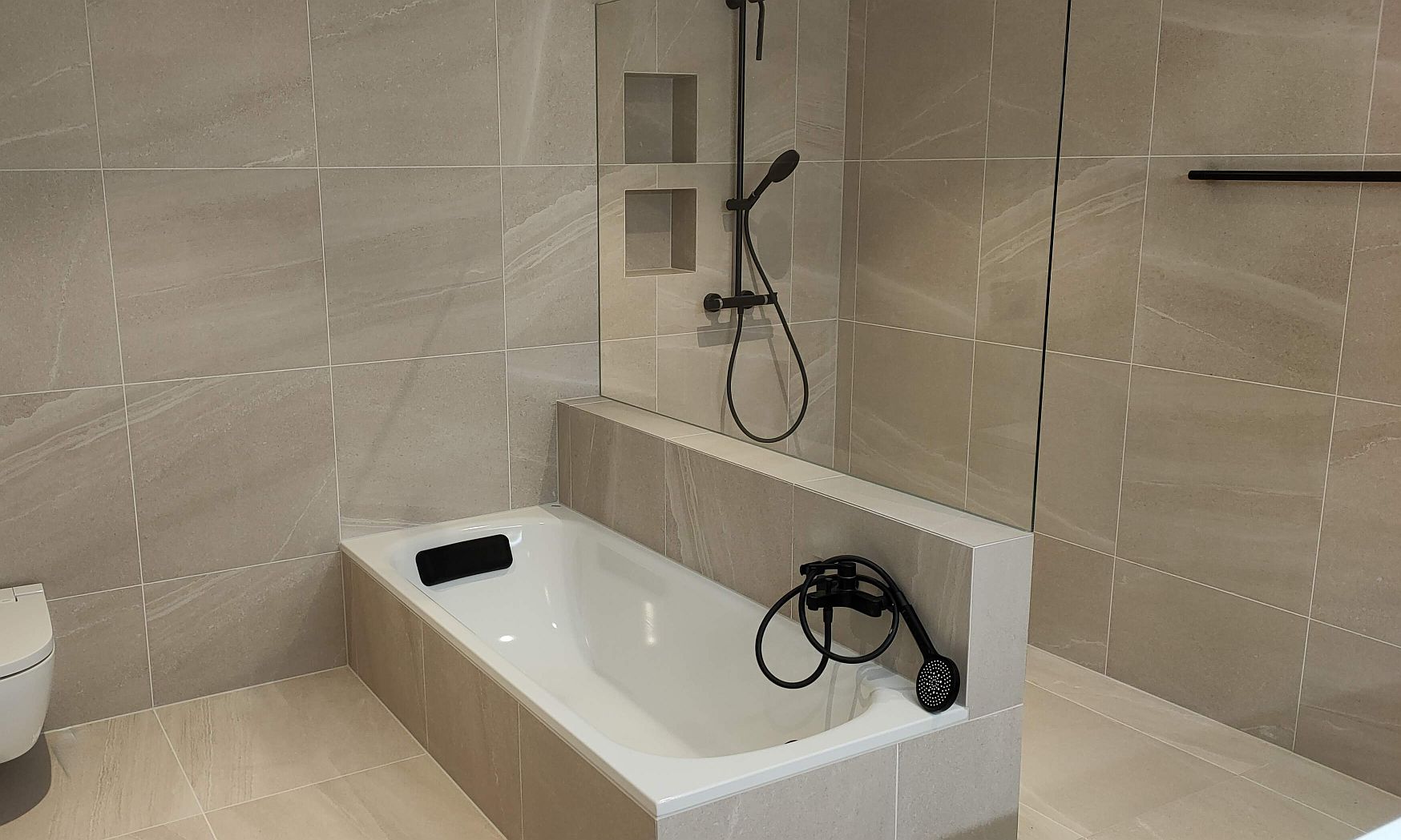 Badewanne mit Glas-Duschtrennwand als Spritzschutz und integrierter Dusche im modernen Badezimmer