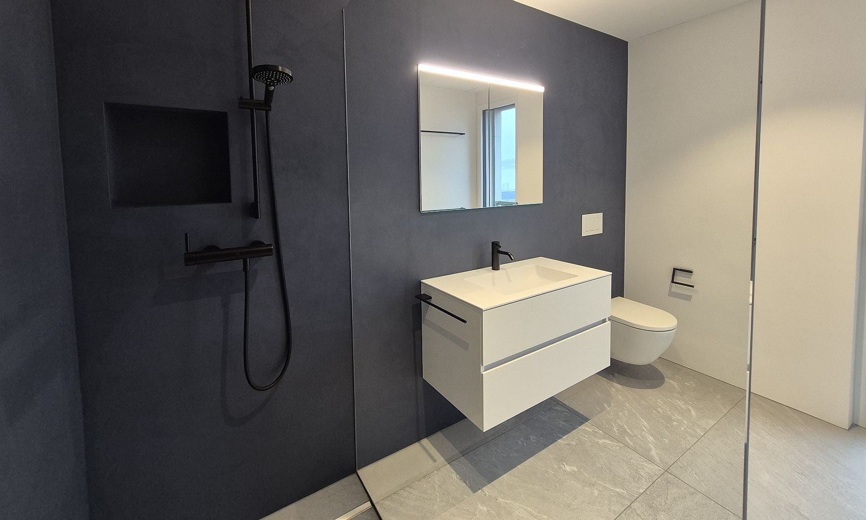 Moderne bodengleiche Dusche mit Glas-Duschtrennwand, schwarzer Regendusche und Waschtisch im modernen Badezimmer.